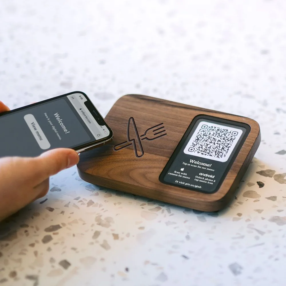 Phone tapping a wooden NFC menu plate on a terrazzo counter